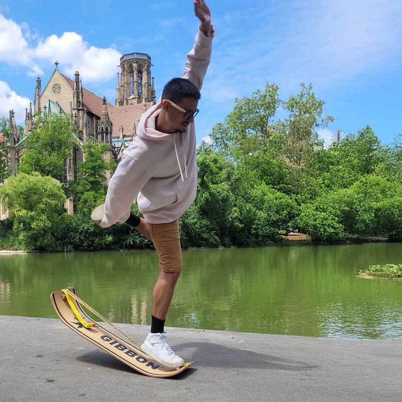 Person slakboarding in a park with trees and a building in the background