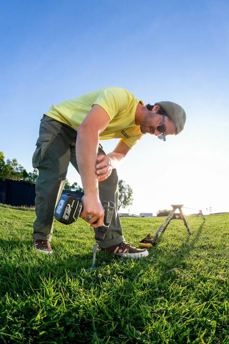 Drilling SlackYard ground screws into the lawn